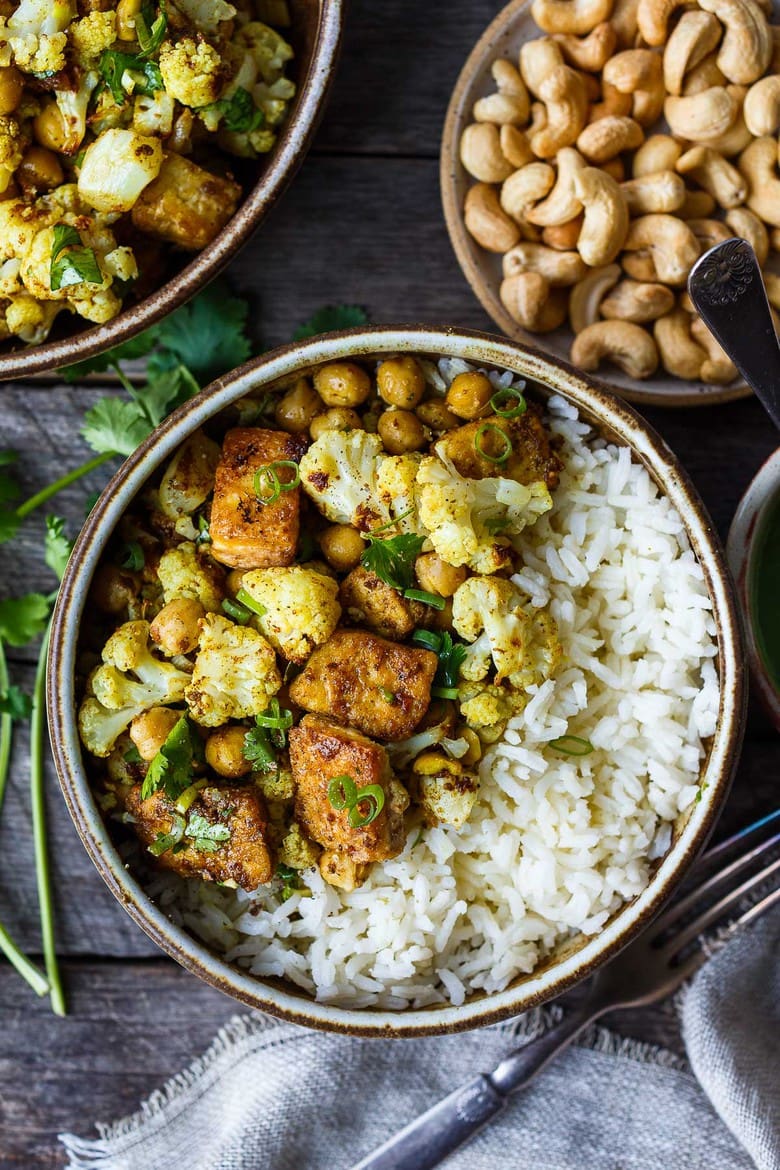 Savory oven-roasted Indian Cauliflower, Chickpea, and Tofu Bowls served over fluffy basmati rice with Cilantro Mint Chutney, seasoned with a simple Madras Curry dressing. A simple dish rich with fragrant spice and amazing flavor.  Healthy,  flavorful, and vegan! (Updated 4/22)