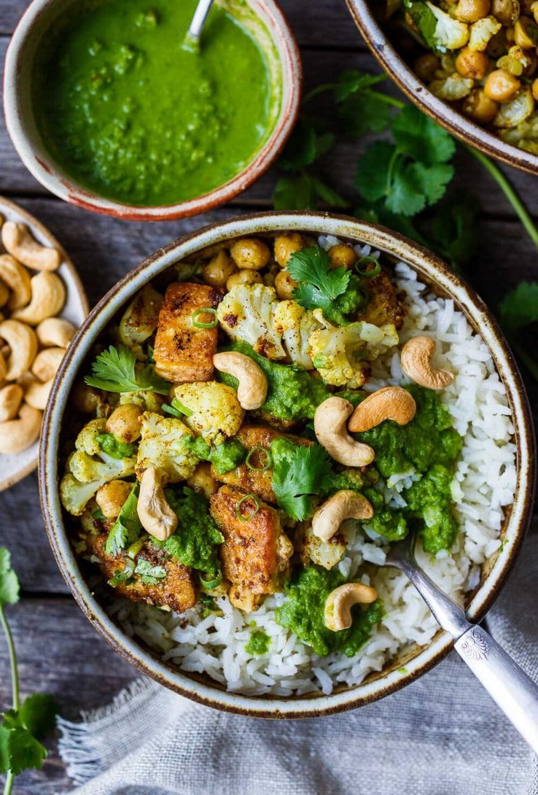 Savory oven-roasted Indian Cauliflower, Chickpea, and Tofu Bowls served over fluffy basmati rice with Cilantro Mint Chutney, seasoned with a simple Madras Curry dressing. A simple dish rich with fragrant spice and amazing flavor.  Healthy,  flavorful, and vegan! (Updated 4/22)
