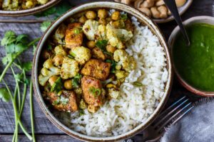 Savory oven-roasted Indian Cauliflower, Chickpea, and Tofu Bowls served over fluffy basmati rice with Cilantro Mint Chutney, seasoned with a simple Madras Curry dressing. A simple dish rich with fragrant spice and amazing flavor.  Healthy,  flavorful, and vegan! (Updated 4/22)