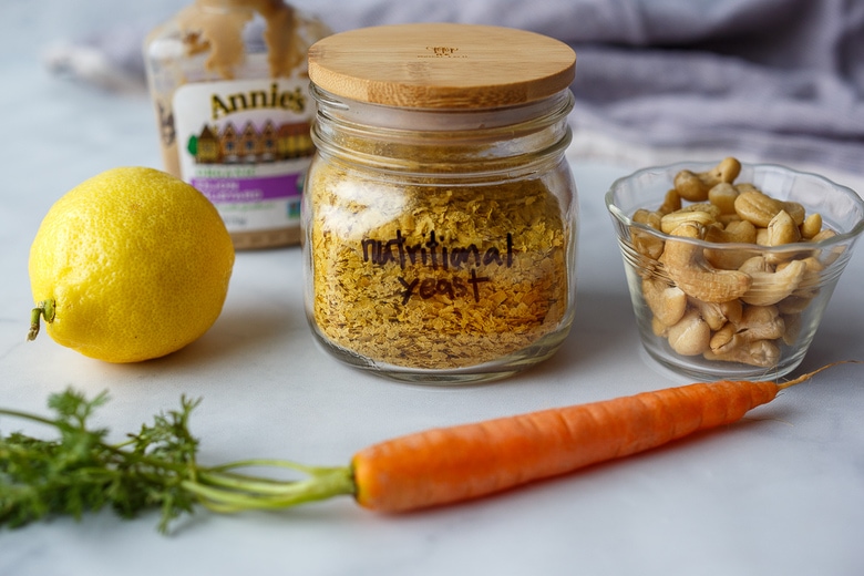 ingredients in vegan hollandaise laid out on counter- nutritional yeast, cashews, lemon, carrot, dijon.