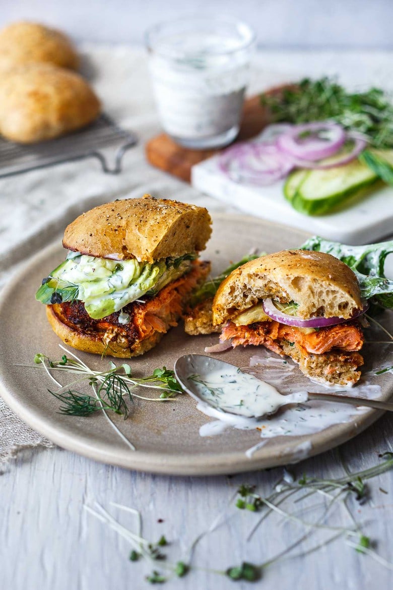 Blackened Salmon Sandwich!  A succulent crispy crusted, cajun spiced, salmon fillet tucked into a toasted bun with fresh greens, cucumber, red onion, drizzled with creamy Dilly Ranch Dressing.