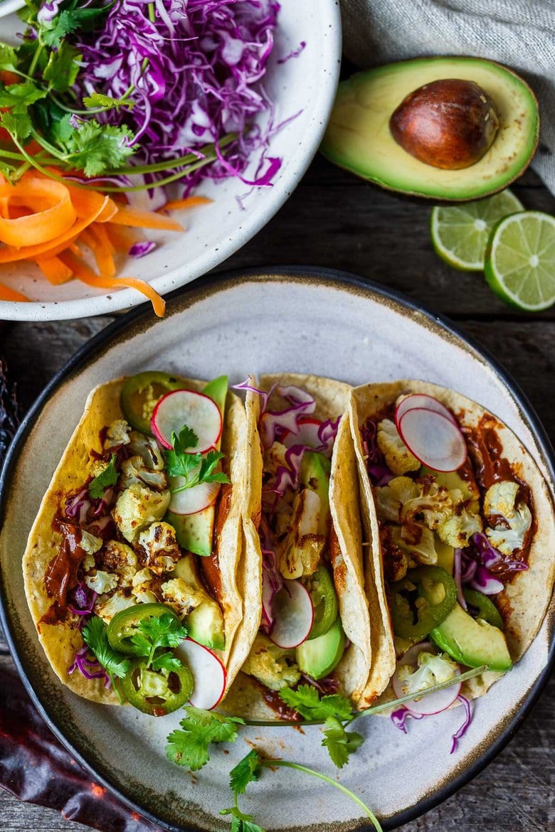 Roasted Cauliflower Tacos with quick and easy Mole Rojo sauce!  These healthy vegan tacos are loaded up with cabbage, avocado, radishes and cilantro and full of satisfying flavor and fresh crunchy ingredients.