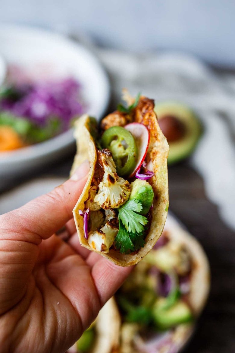 Roasted Cauliflower Tacos with quick and easy Mole Rojo sauce!  These healthy vegan tacos are loaded up with cabbage, avocado, radishes and cilantro and full of satisfying flavor and fresh crunchy ingredients.