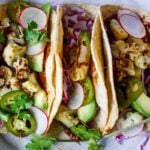 Roasted Cauliflower Tacos with quick and easy Mole Rojo sauce! These healthy vegan tacos are loaded up with cabbage, avocado, radishes and cilantro and full of satisfying flavor and fresh crunchy ingredients.