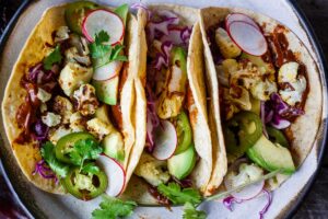 Roasted Cauliflower Tacos with quick and easy Mole Rojo sauce!  These healthy vegan tacos are loaded up with cabbage, avocado, radishes and cilantro and full of satisfying flavor and fresh crunchy ingredients.