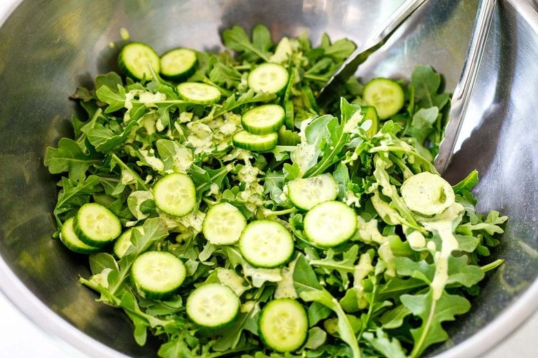 add arugula, cucumbers and dressing to a large bowl.