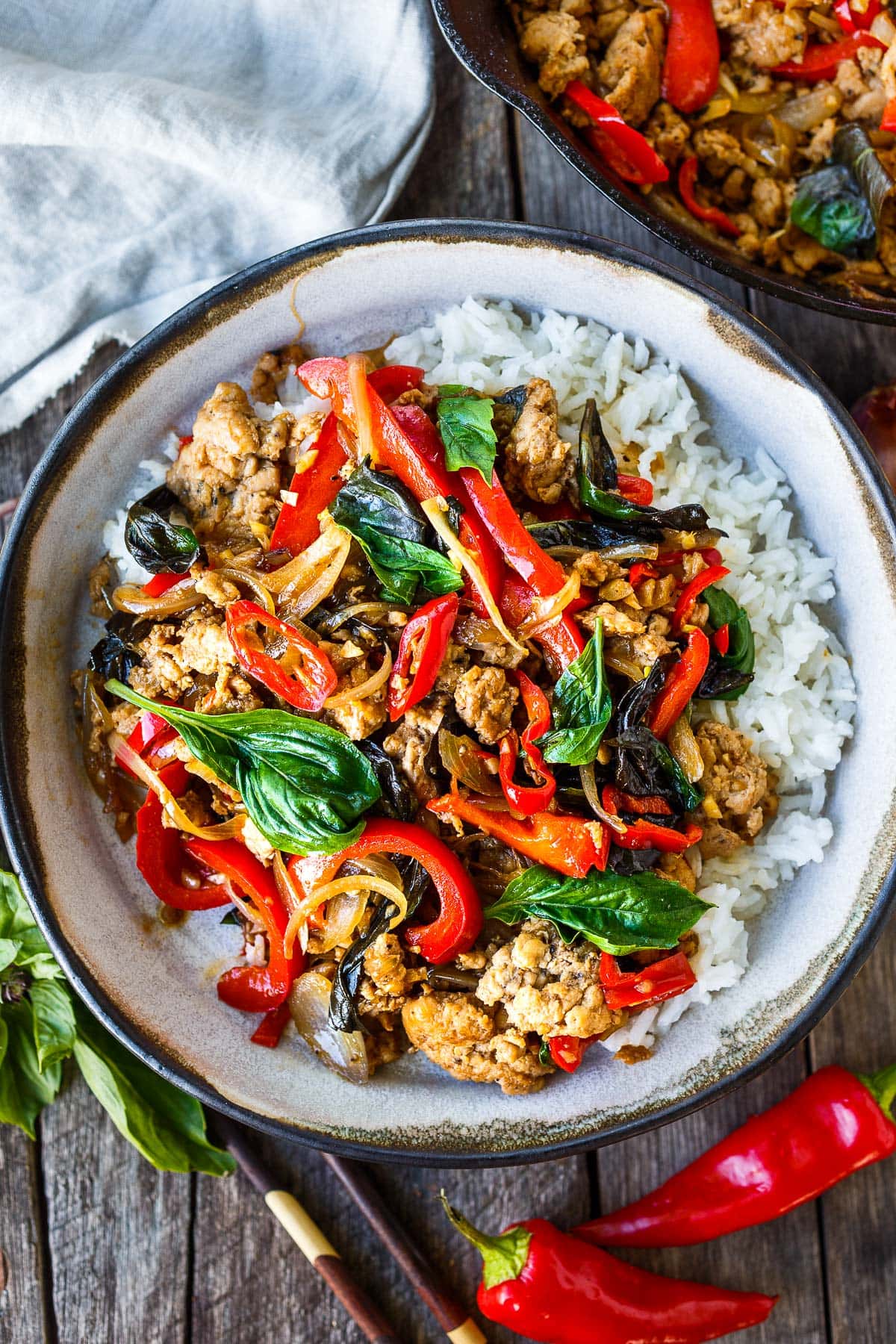 Thai basil chicken on rice with peppers, with chopsticks on the bowl.