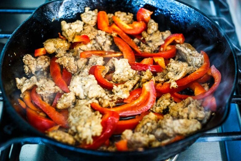 Mixing peppers with browned chicken for Thai basil chicken.