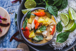 pineapple curry in a circular bowl garnish with basil and lime wedges