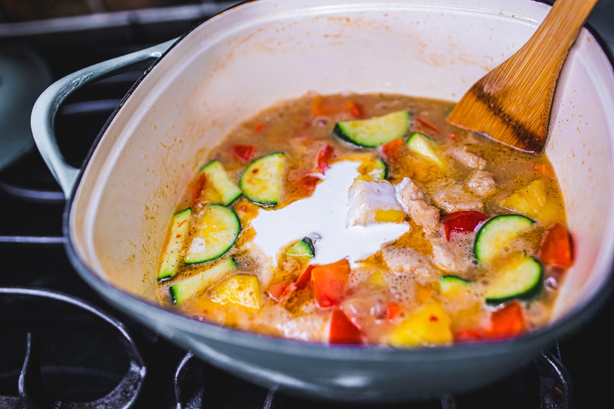 adding more coconut milk to the pot