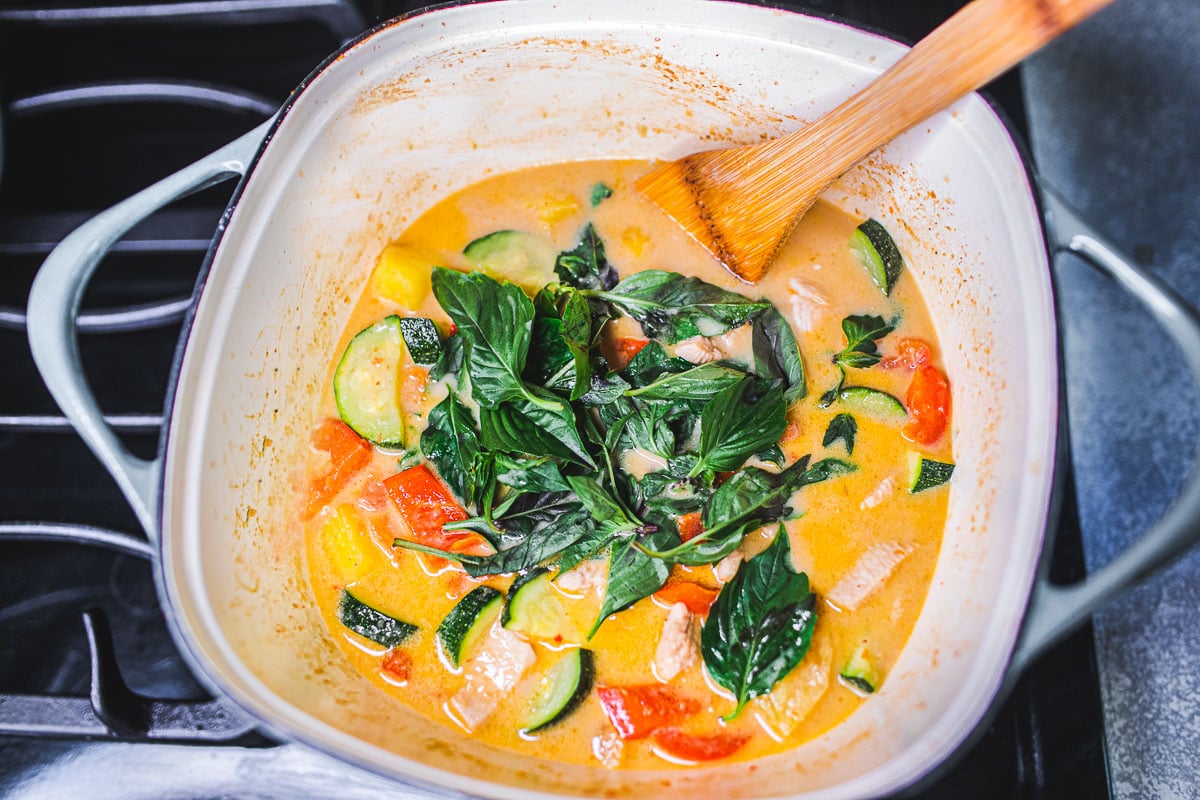 adding thai basil to the pineapple curry