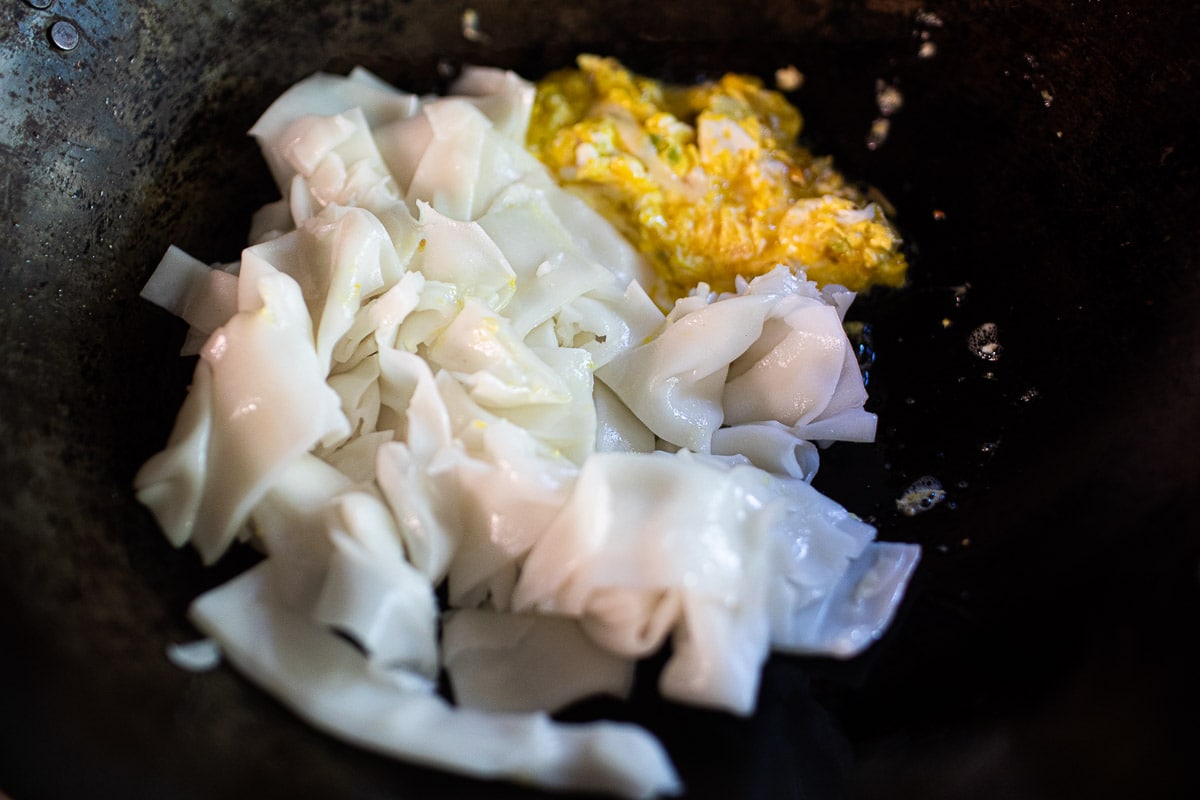 wide noodles and scrambled egg in a wok