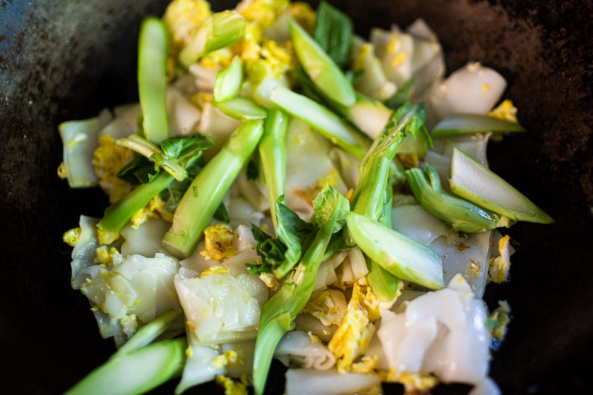 chinese broccoli over rice noodles in a wok