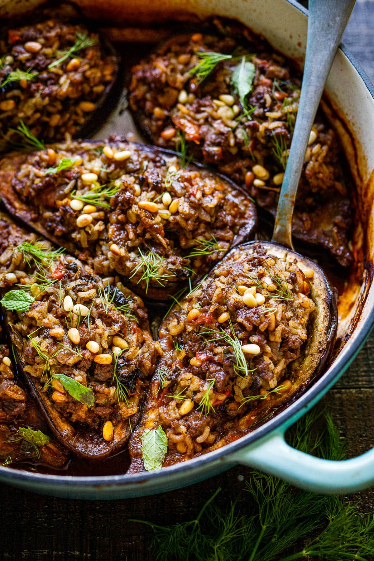  Stuffed Eggplant in a bking dish wiht a serving spoon. 