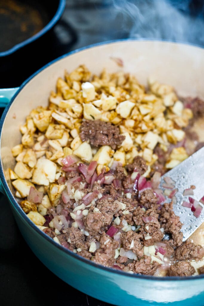 Adding eggplant to the meat saute.