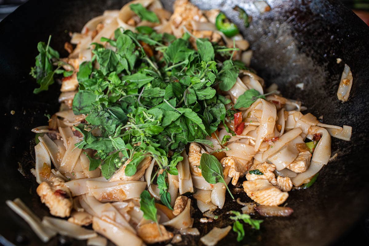 basil over rice noodles in a wok