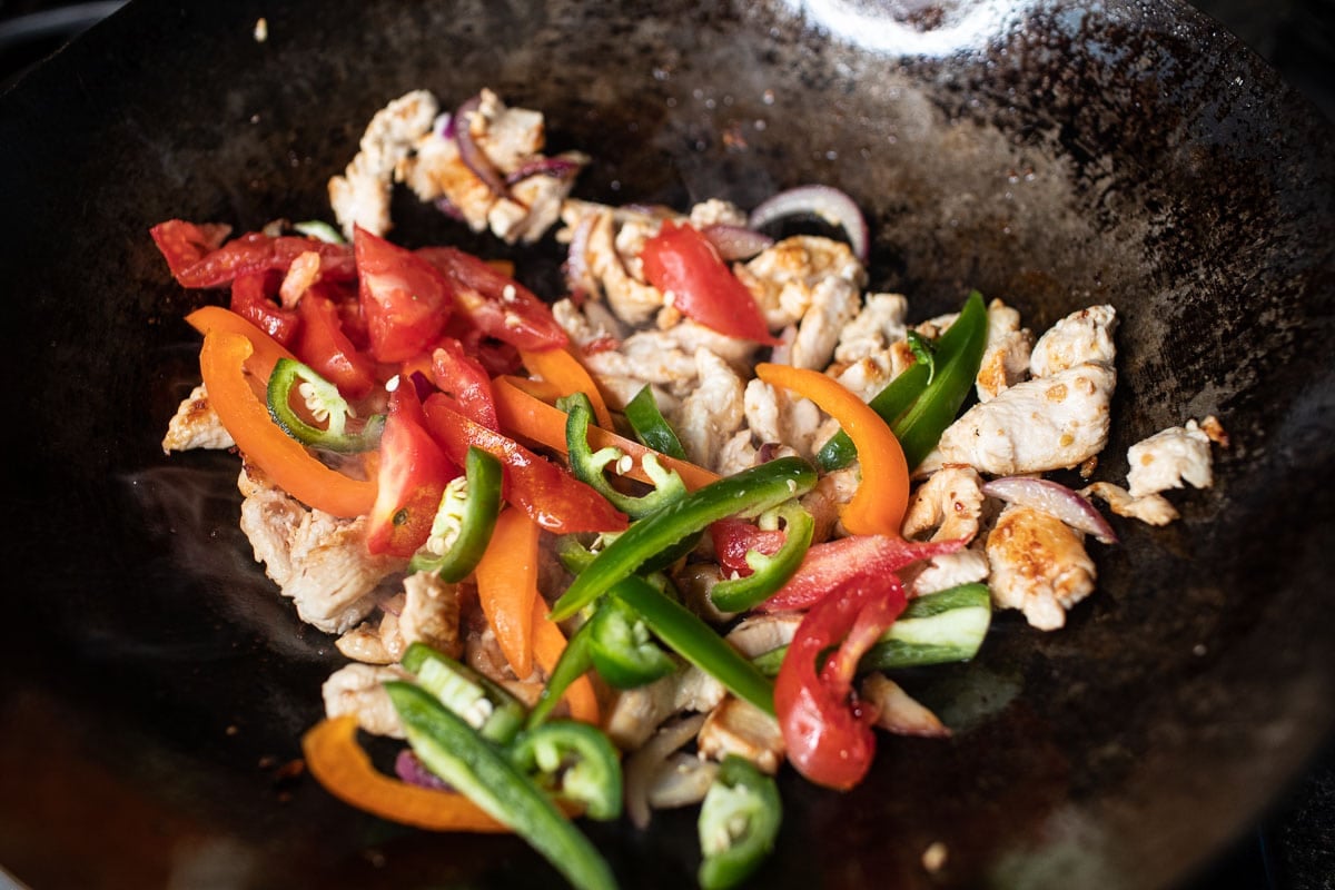 chicken, peppers and tomotoes stir fried in a wok