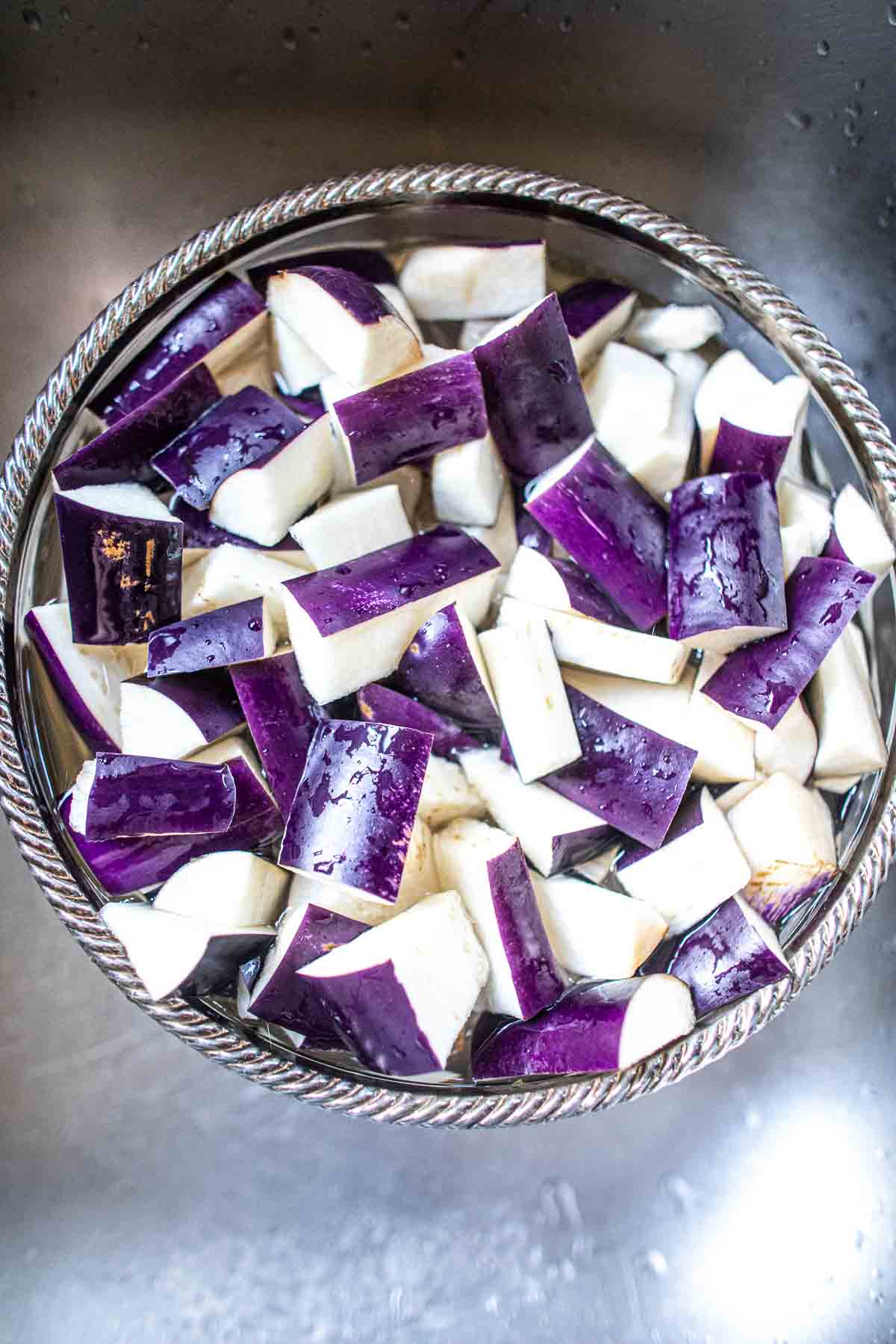 cut eggplants soaking in bowl of water