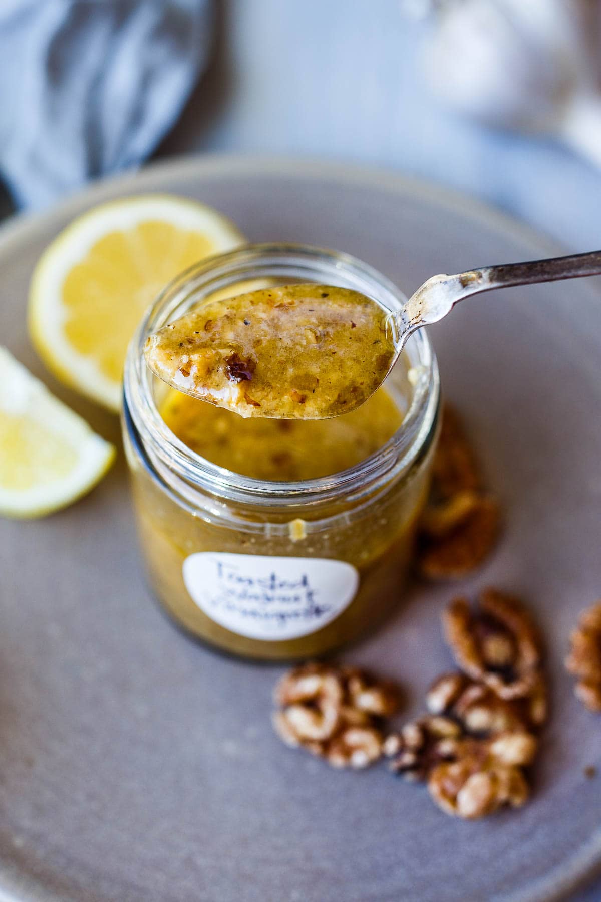 Toasted walnut vinaigrette in a jar with a label and spoon.