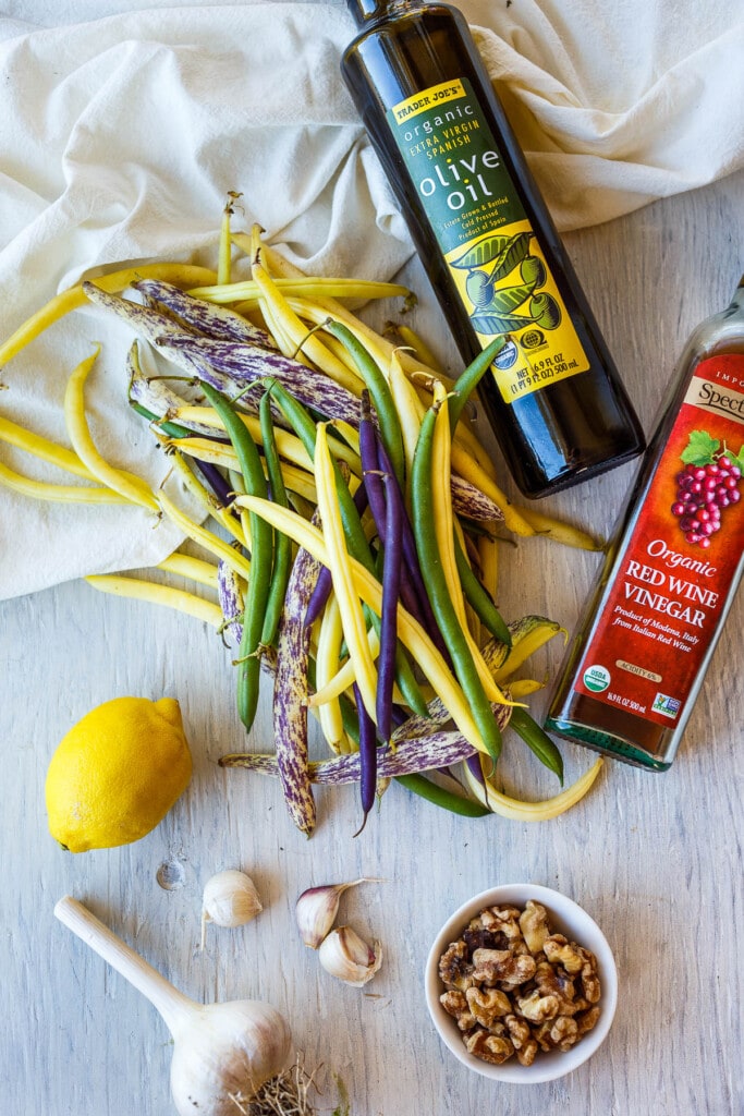 Fresh colored green beans and ingredients for walnut vinaigrette.