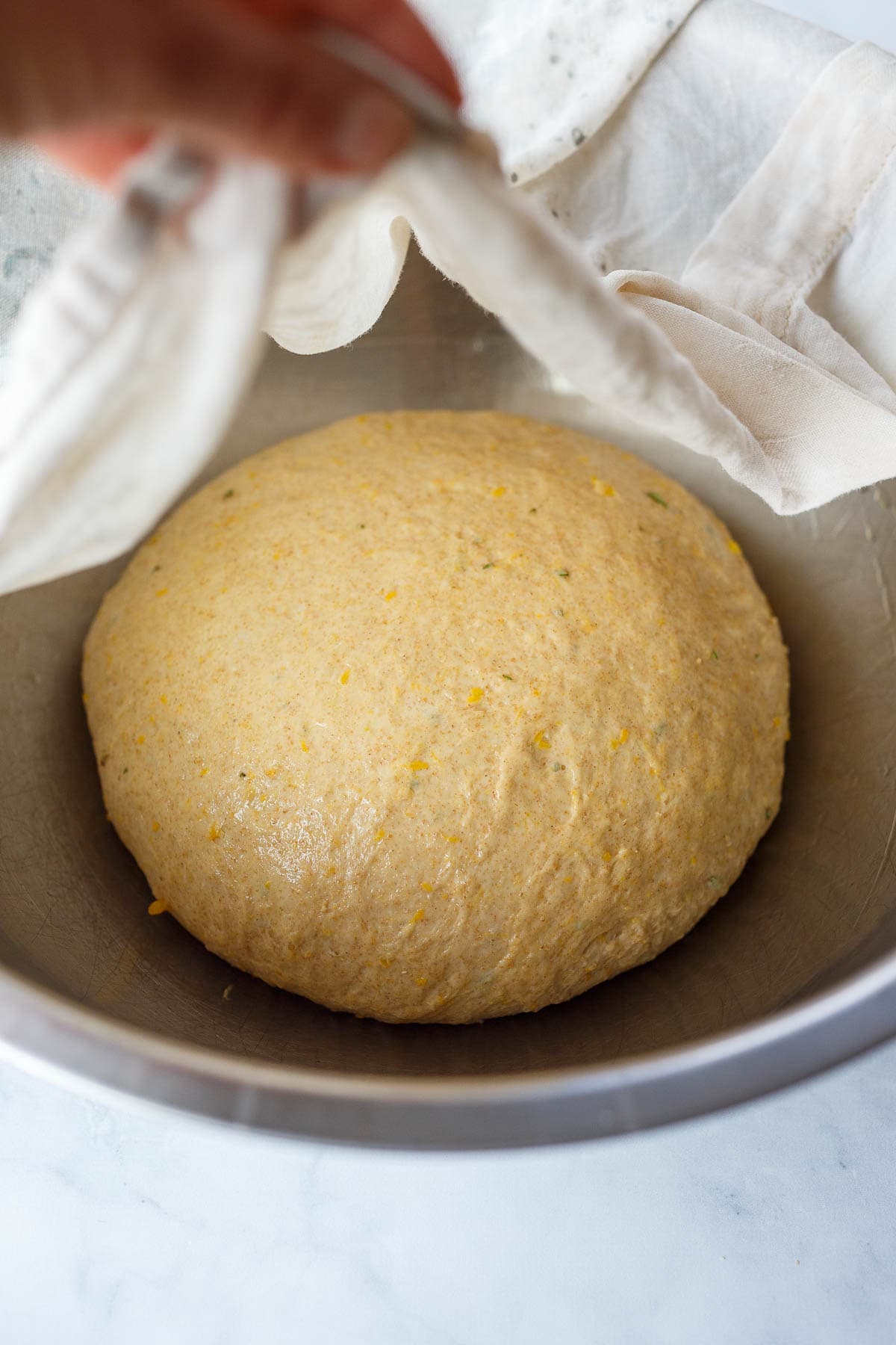 Dough proofing in a metal bowl covered.