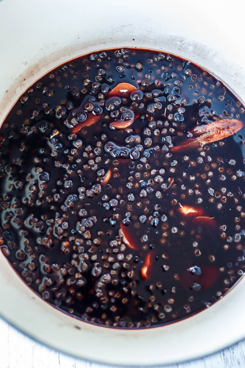 Simmering elderberries with water and ginger.