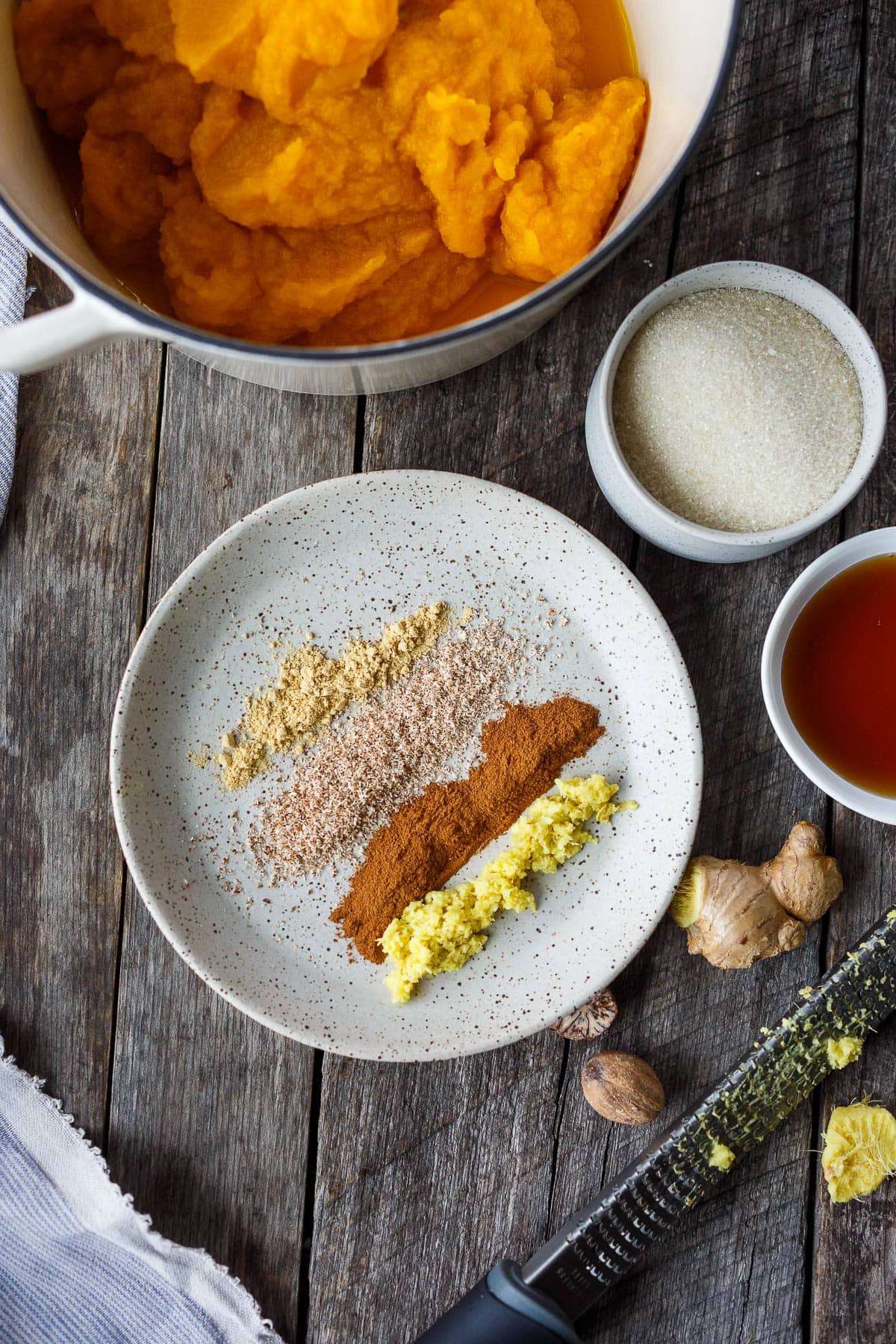 Spices, sugar, maple syrup, and fresh pumpkin puree reading for cooking.