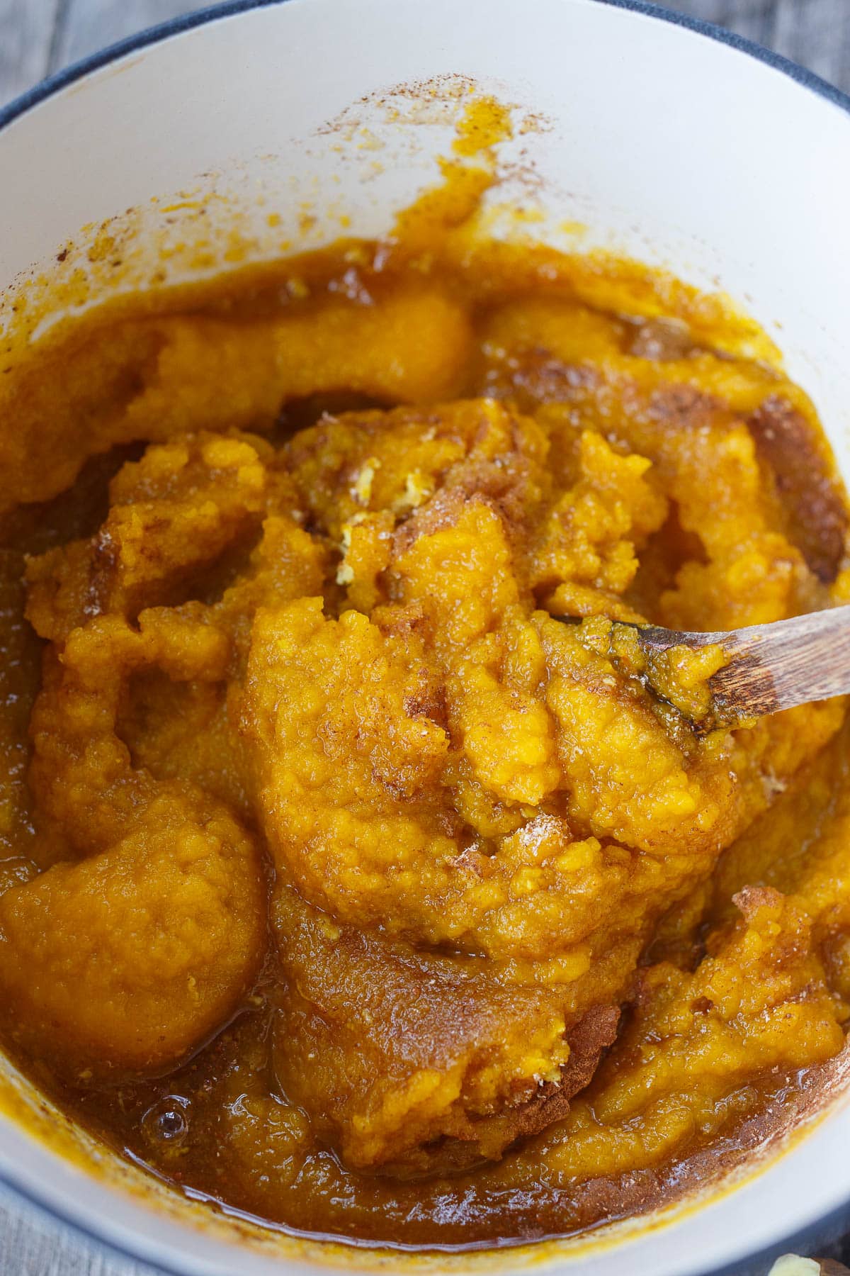 Stirring all ingredients of pumpkin butter in a stock pot with a wooden spoon.