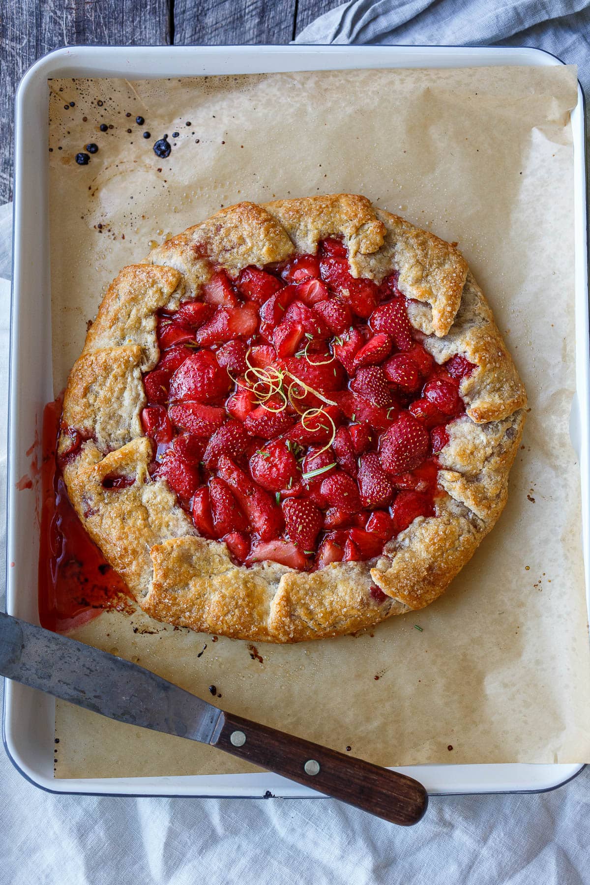 This Strawberry Galette is bright, cheery, and full of springtime flavor. Lemon and rosemary perfectly complement the sweet-tart berries. A rustic flaky rye pastry crust encloses the succulent filling.