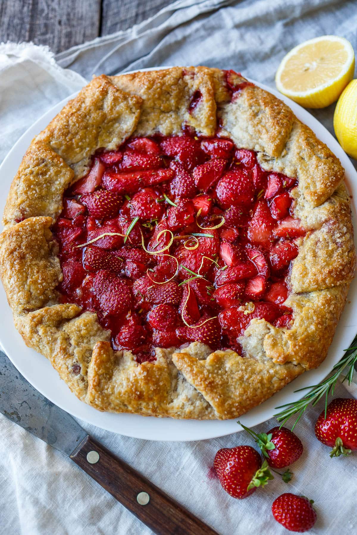 This Strawberry Galette is bright, cheery, and full of springtime flavor. Lemon and rosemary perfectly complement the sweet-tart berries. A rustic flaky rye pastry crust encloses the succulent filling.