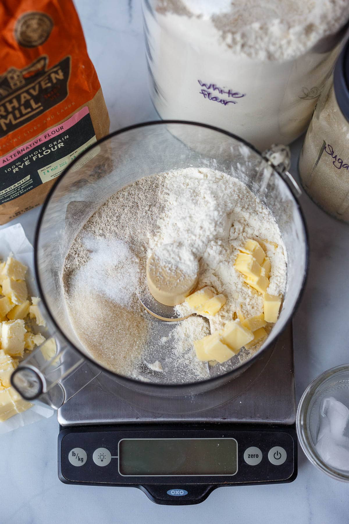 Flour and butter in a food processor, on a scale.