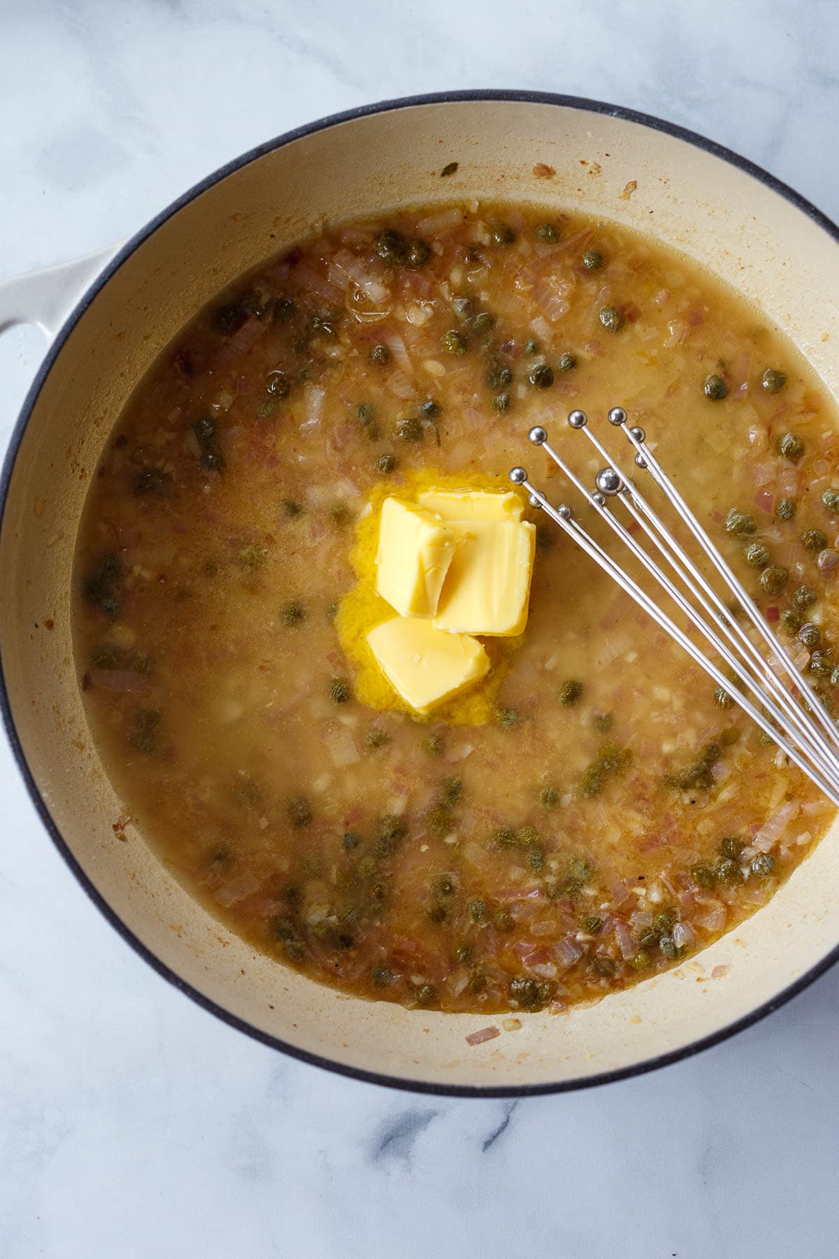 Whisking butter in the caper wine sauce.