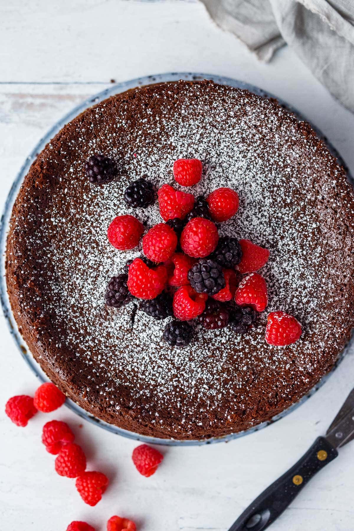 A whole Flourless  Chocolate Torte with fresh berries and powdered sugar.