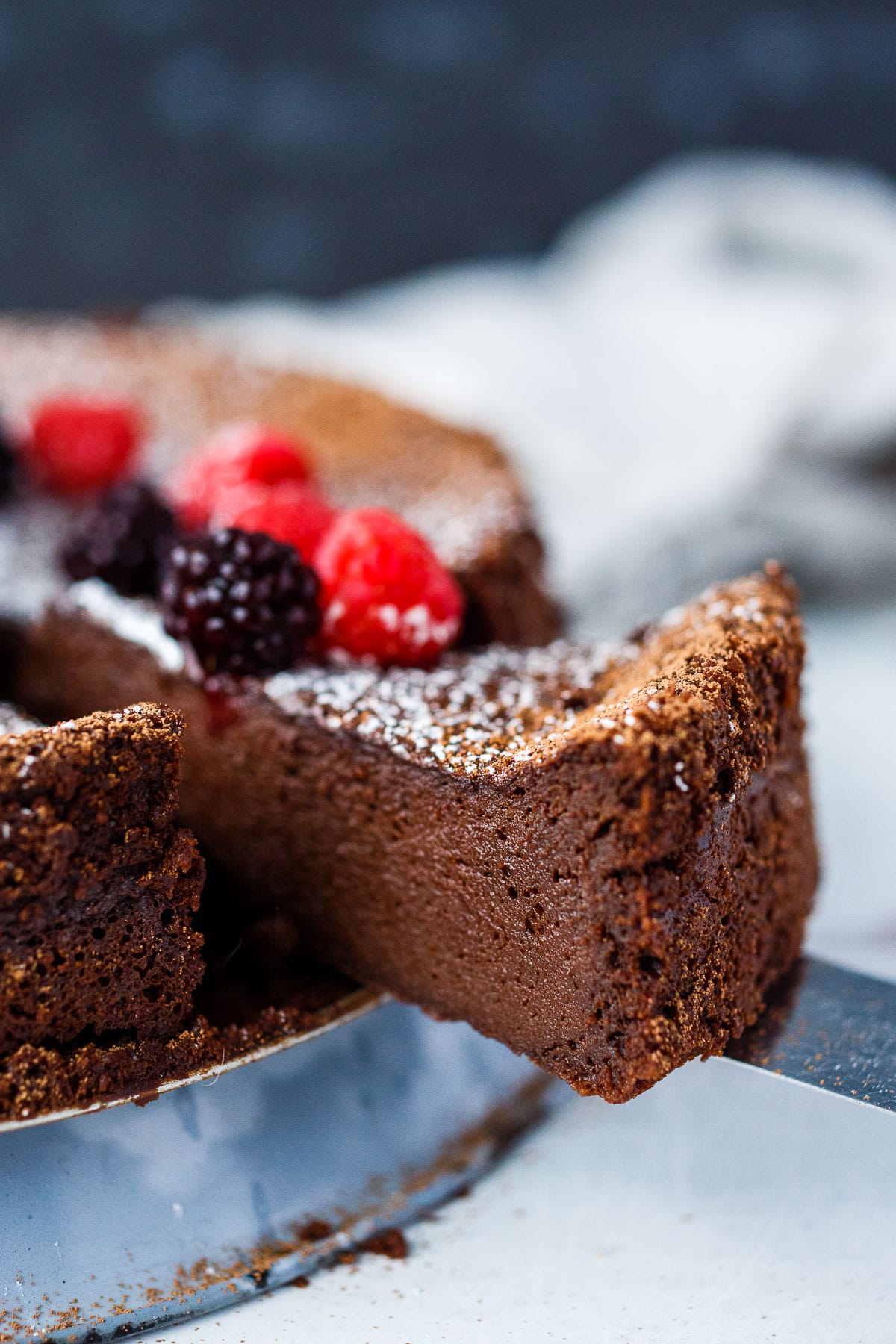 A piece of chocolate torte with powdered sugar and berries.
