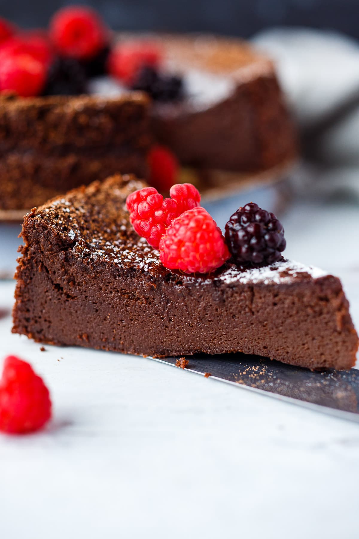 A slice of Flourless  Chocolate Torte with berries. 