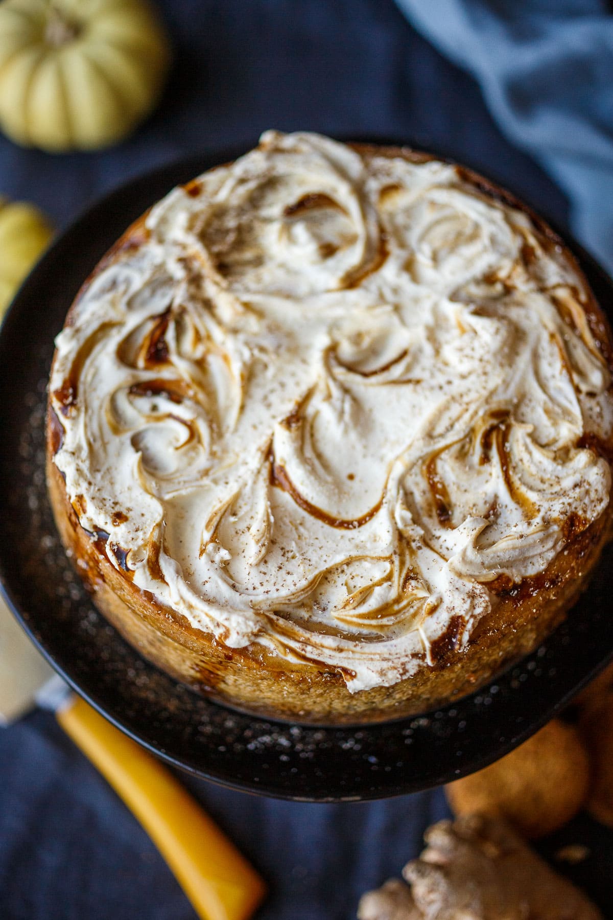 a finished pumpkin cheesecake topped with cream and caramel, unsliced, fresh out of the oven.