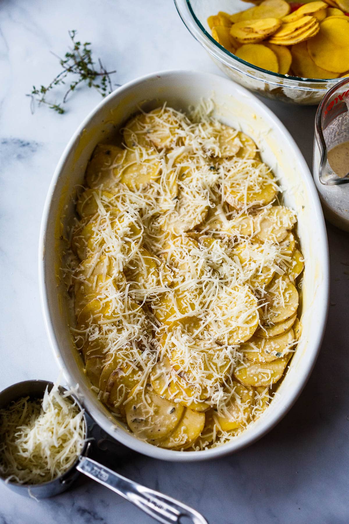 Layering potatoes with cream and cheese.