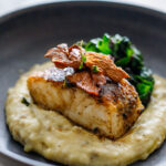 halibut coated in mushroom powder and pan seared, topped with sautéed mushrooms over sunchoke puree in a bowl.