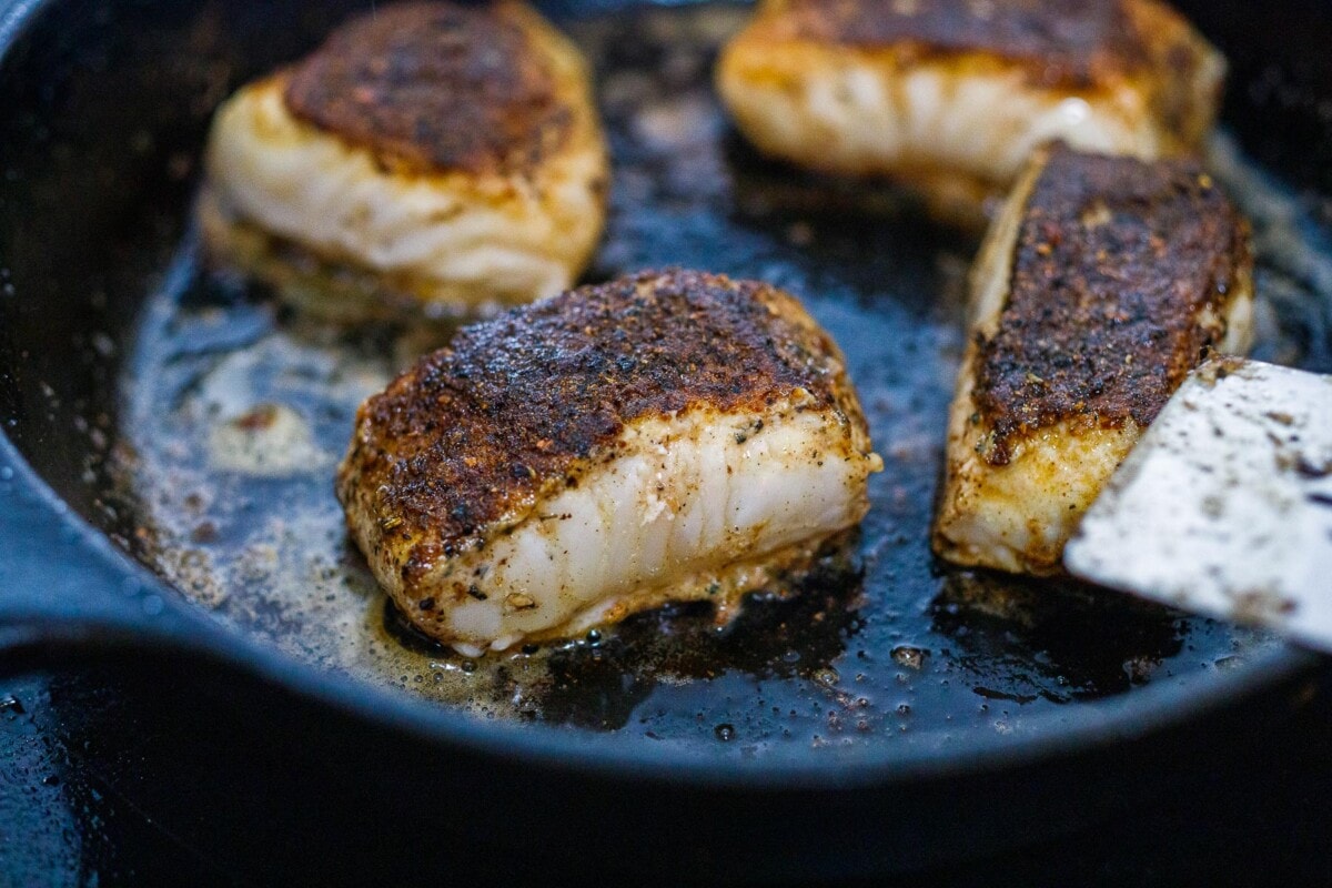 halibut in a skillet being seared. 