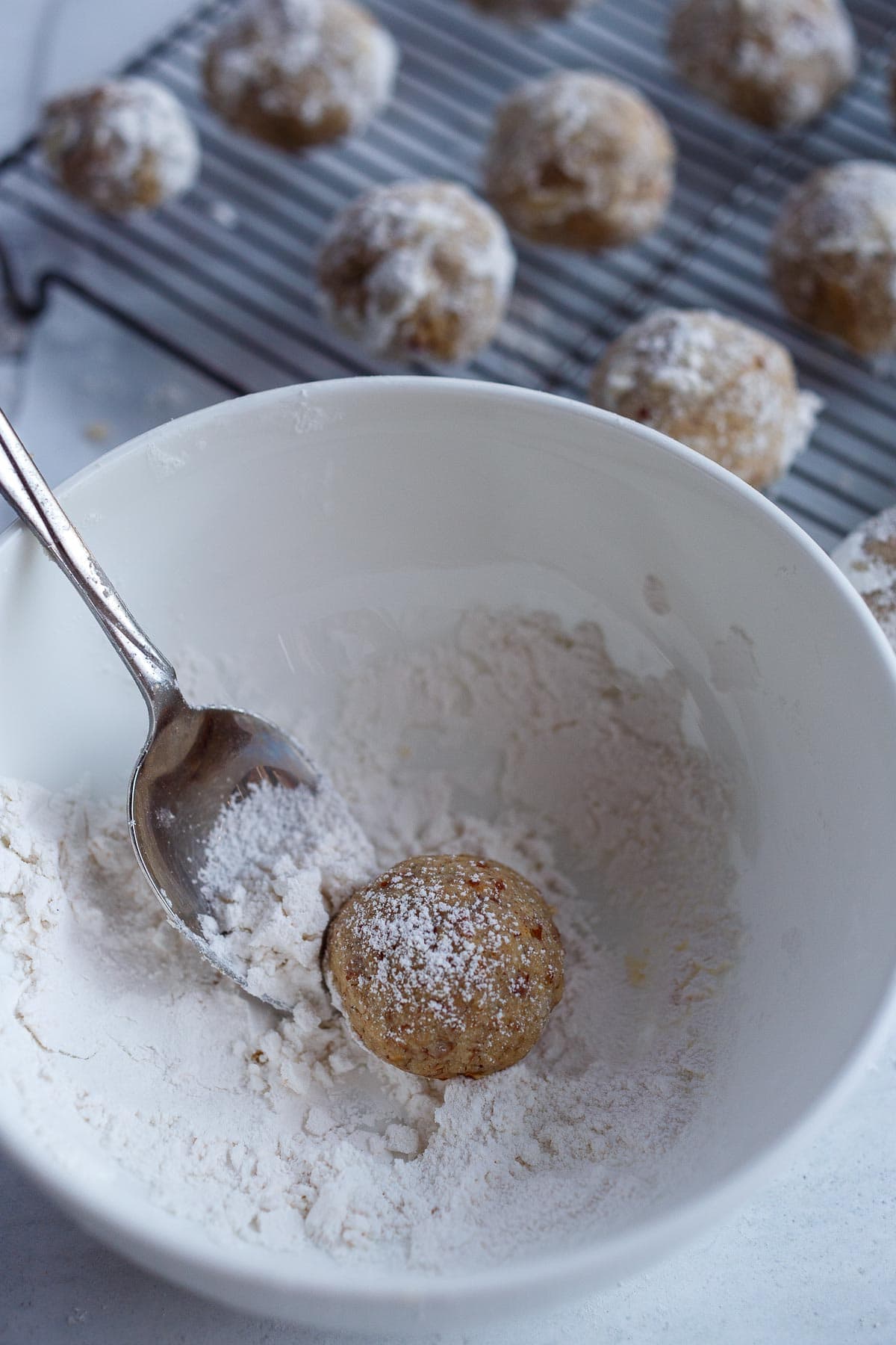 Warm cookies in a bowl of powdered sugar.