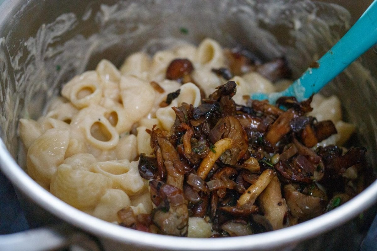 Adding half of the saut&eacute;ed mushrooms to the Mac and cheese. 