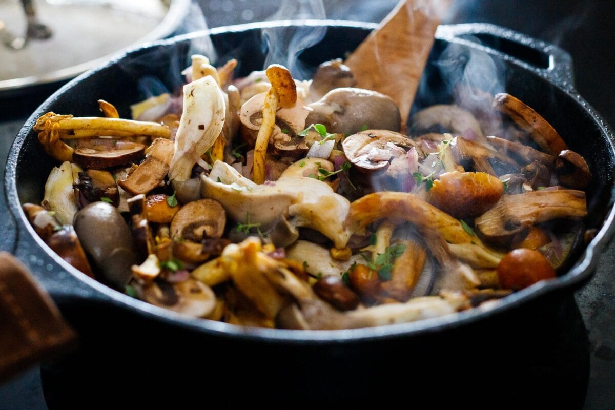 Mushrooms sautéing in a skillet.
