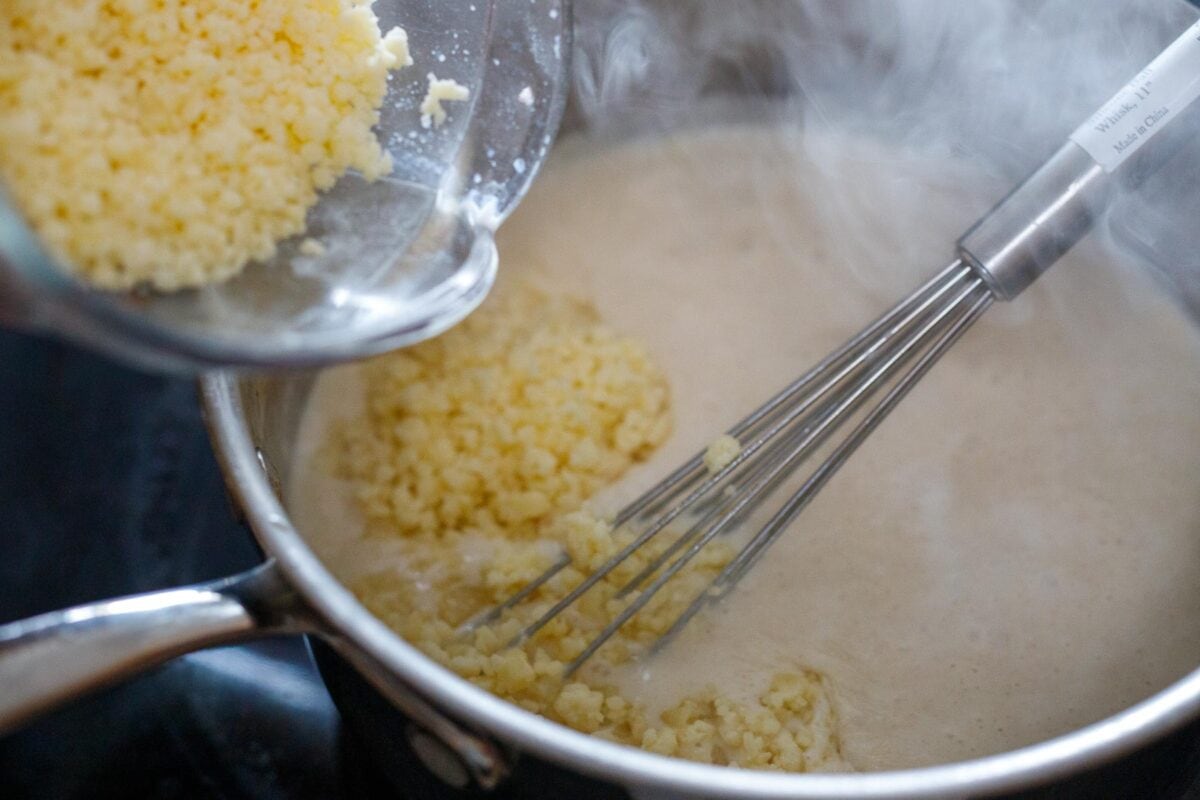 Whisking in grated cheese to the sauce.