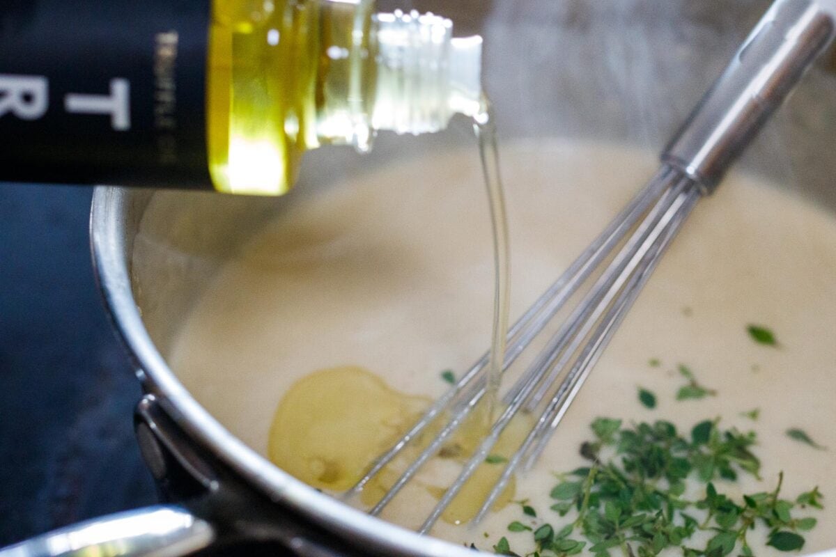 Adding truffle oil to the béchamel sauce.