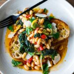Brothy Beans with lacinato kale, roasted peppers, olives, capers and lemon zest over garlic-infused Sourdough Bread -a simple pantry meal that can be made in under 30 minutes! Vegan adaptable.
