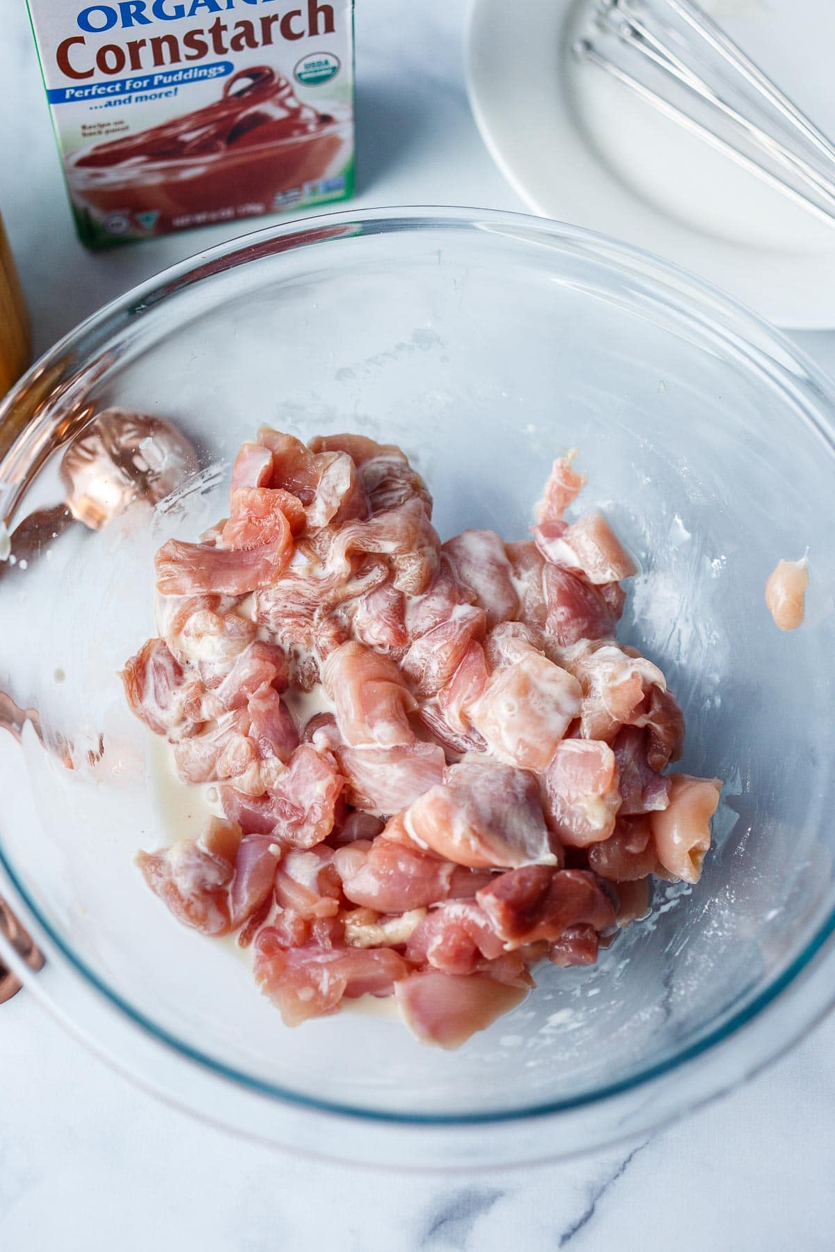 Chicken tossed with cornstarch in a bowl.