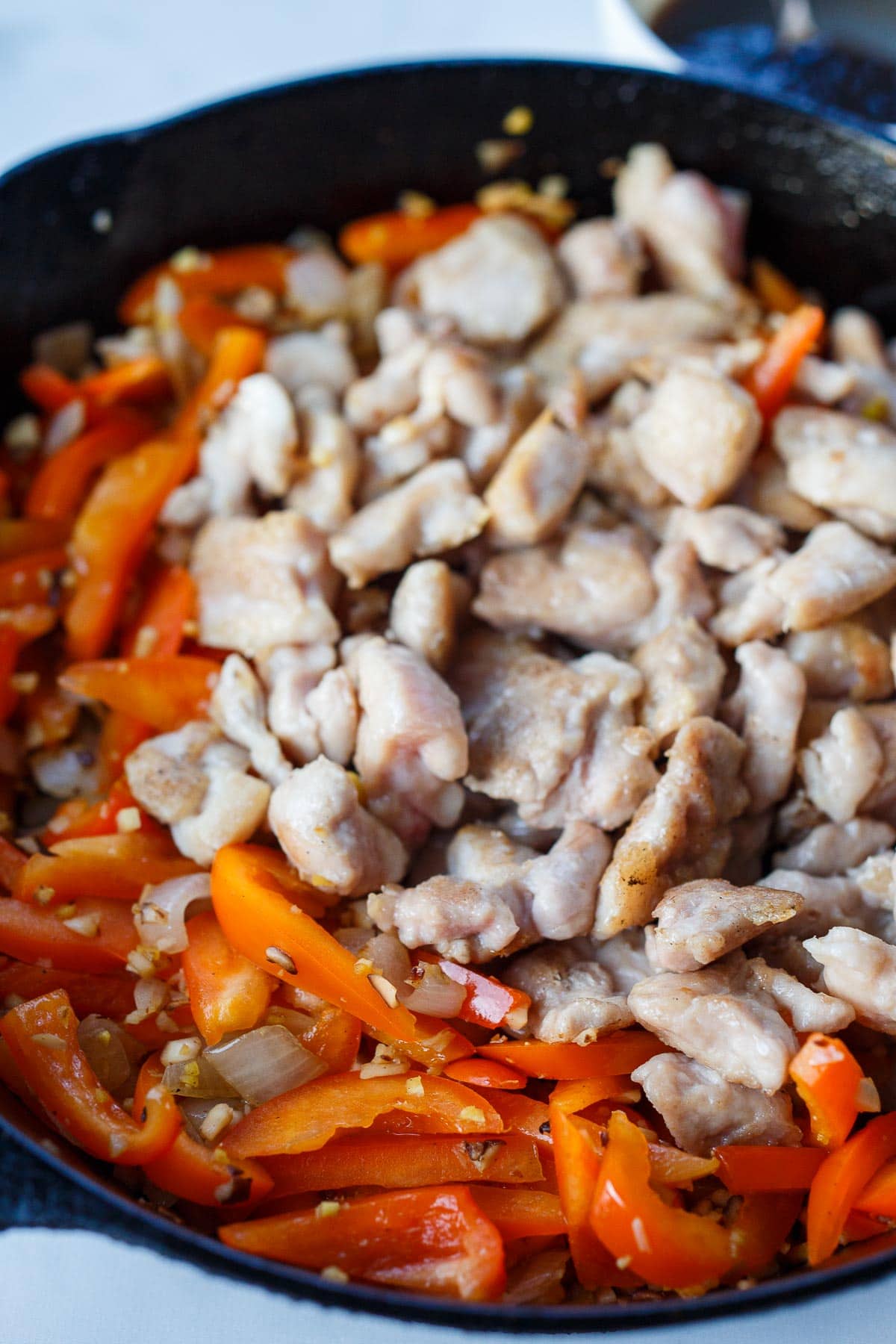 Adding chicken and bell peppers in the sauté pan.