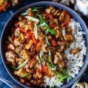 cashew chicken in bowl with rice and scallions.