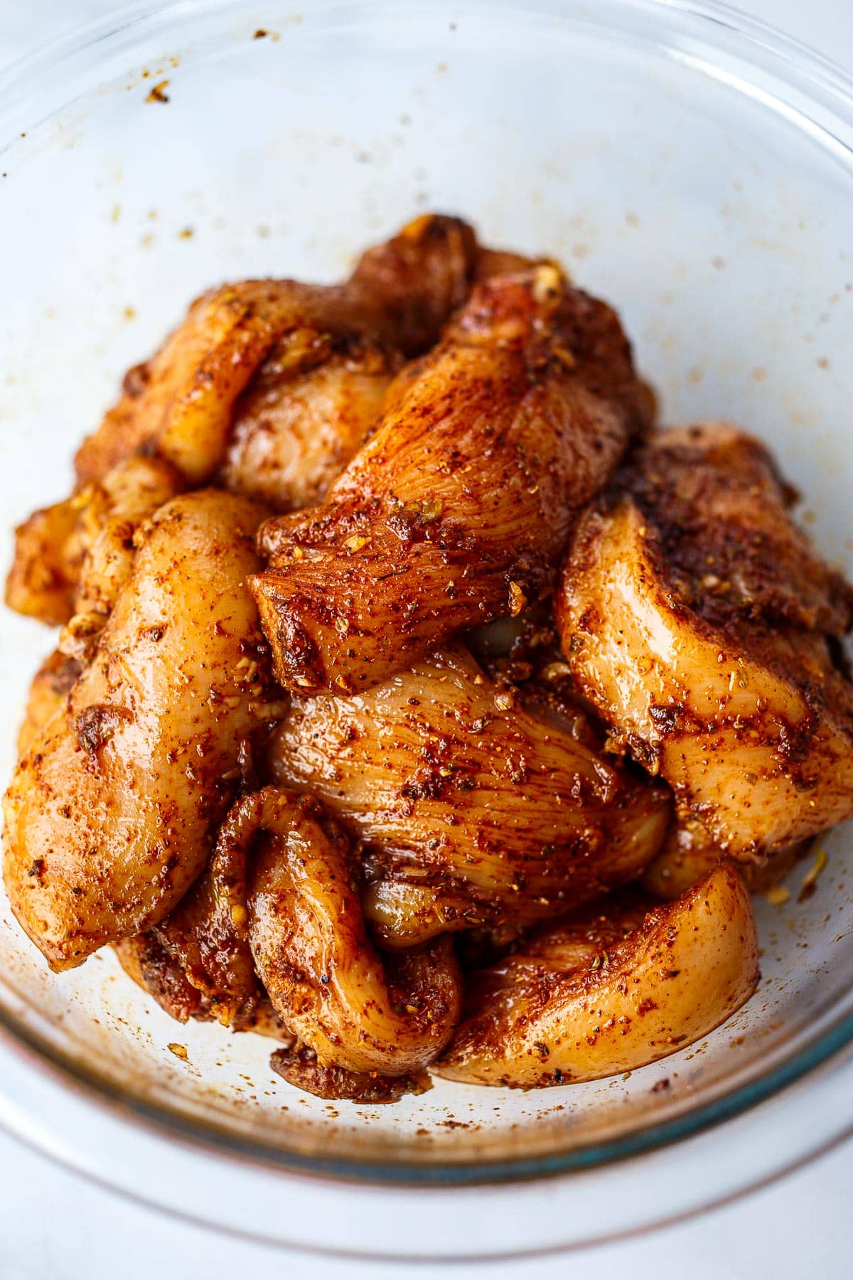 Chicken rubbed with marinade in a bowl.