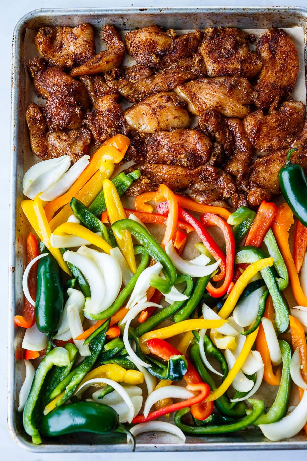 Chicken and peppers on a baking sheet.